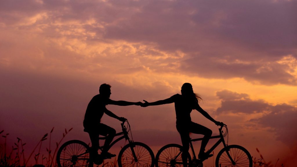 čovjek i žena na biciklu se drže za ruke