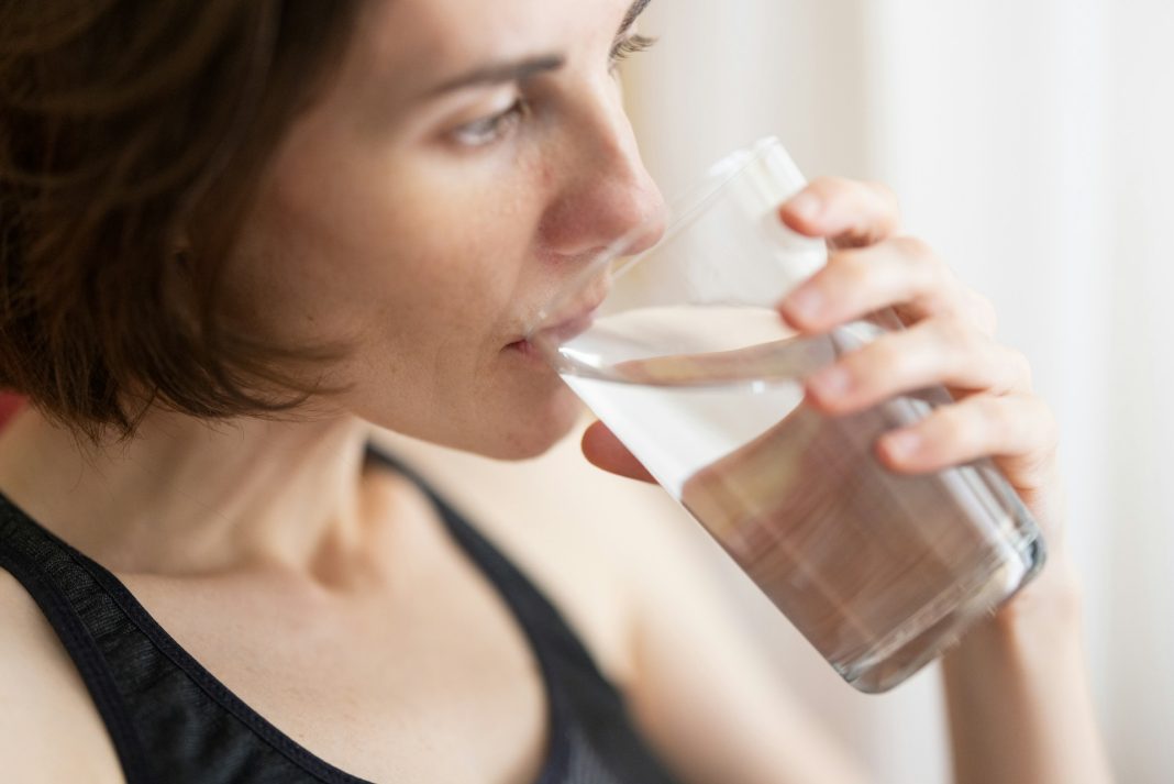 žena pije vodu iz čaše